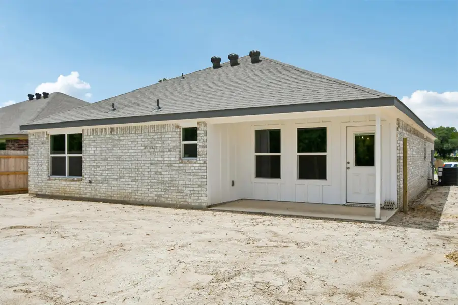 A newly constructed residence showcases a light brick exterior, a paved patio, and a shingle roof under a clear sky. A newly constructed residence showcases a light brick exterior, a paved patio, and a shingle roof under a clear sky.