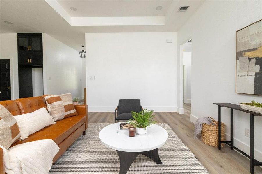 Living room featuring light hardwood / wood-style floors and a raised ceiling