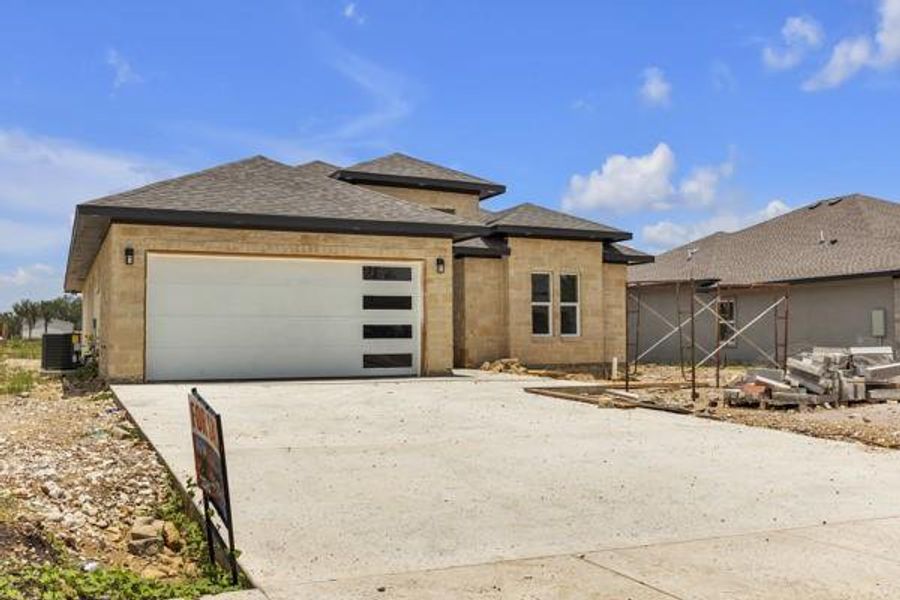 View of front of home with driveway, an attached garage, and a shingled roof