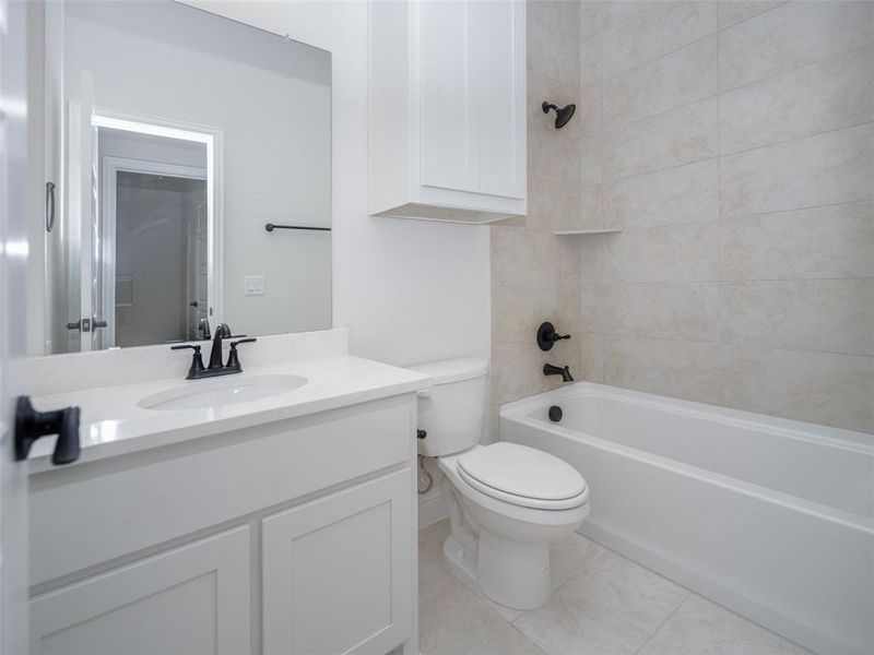 Full bathroom featuring bathtub / shower combination, vanity, and light tile patterned floors Full bathroom featuring bathtub / shower combination, vanity, and light tile patterned floors