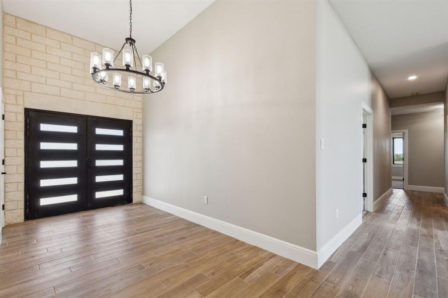 Entrance foyer featuring baseboards, wood look tile floors, and an inviting chandelier Entrance foyer featuring baseboards, wood look tile floors, and an inviting chandelier