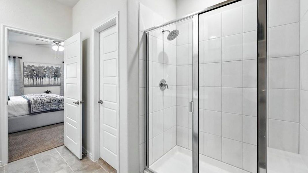 Spacious shower with tiled walls and a glass enclosure, featuring a rain shower head and a polished chrome fixture