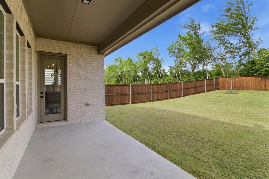 Covered patio with concrete surface, light brick exterior, and a glass-paneled door