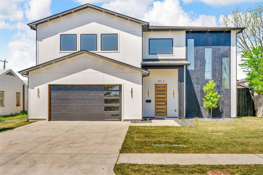 View of front of home featuring concrete driveway, stucco siding, a front yard, a garage, and fence