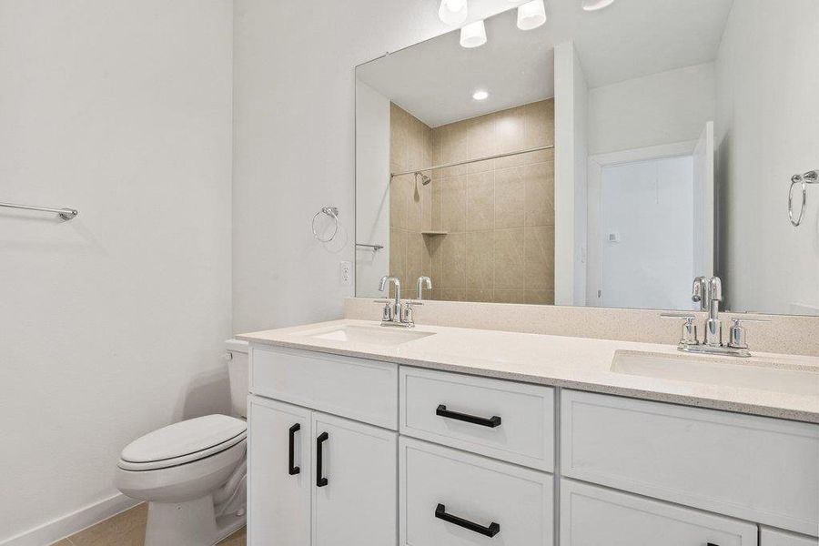 Bathroom featuring double vanity and tiled shower