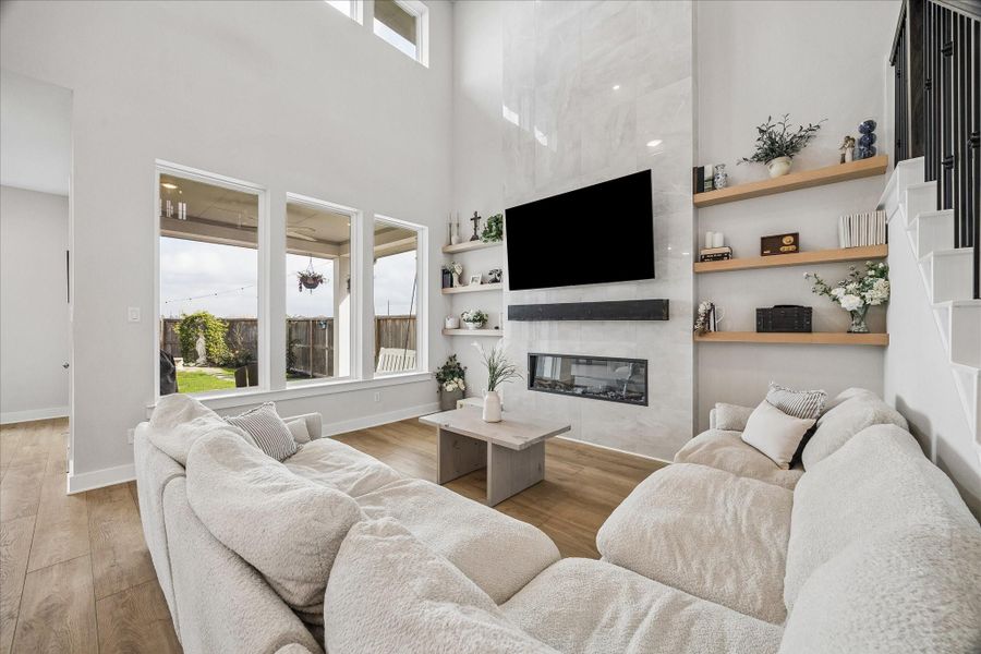 A stunning fireplace with floating mantel and built-in shelving anchors the living space, while large windows fill the room with natural light.