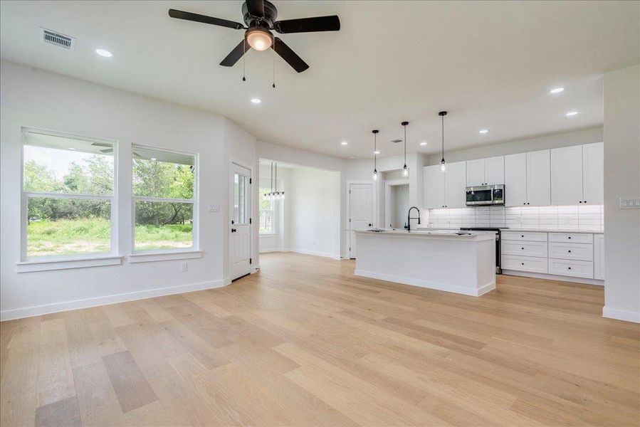 Open-concept living space with a modern kitchen in view, featuring wood flooring and ample natural light.