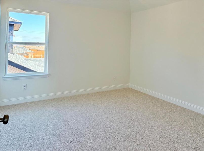 Carpeted spare room featuring baseboards