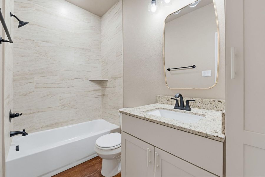 Full bath with vanity,  shower combination, and dark wood-type flooring