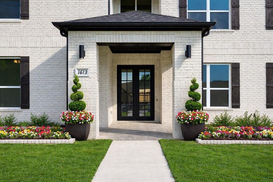Doorway to property featuring french doors, brick siding, and a yard