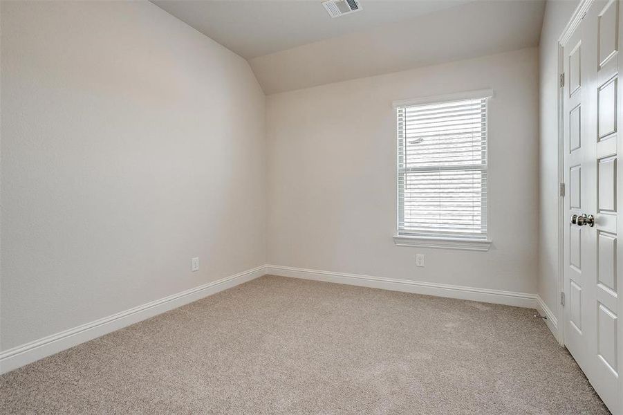 Unfurnished bedroom featuring light carpet and vaulted ceiling