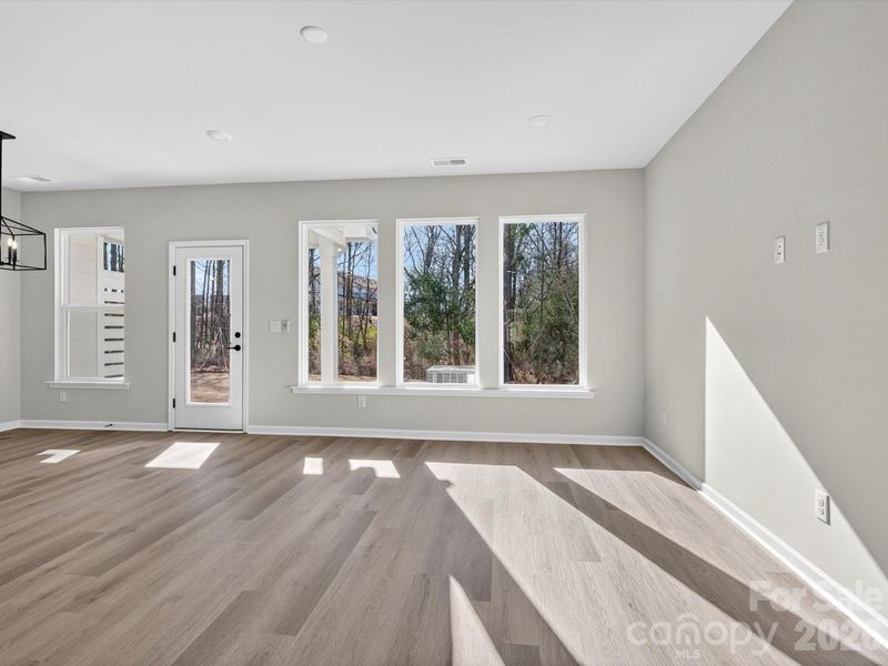 Light filled living room with picture windows allowing natural light to fill the space & views of the yard & woods