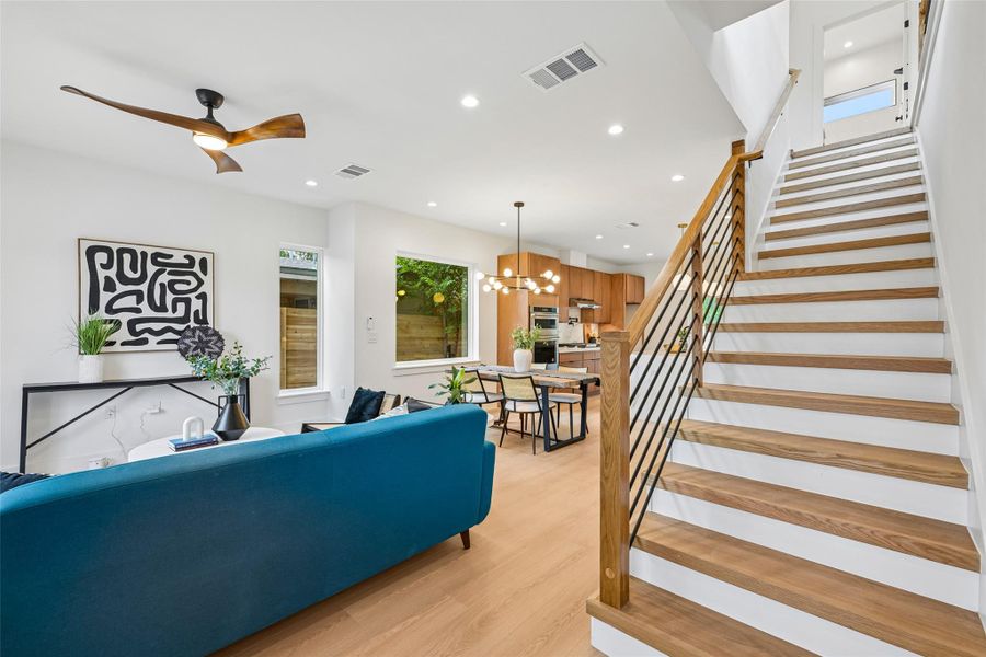 An open concept living area with wood based laminate flooring, abundant natural light, and a modern staircase with white oak treads.