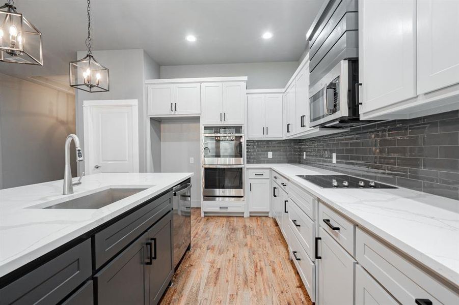 Kitchen with stainless steel appliances, white cabinetry, and a sink Kitchen with stainless steel appliances, white cabinetry, and a sink