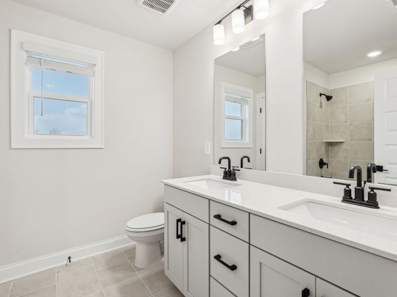 The secondary bathroom comes with dual-vanity sinks and a tub shower.