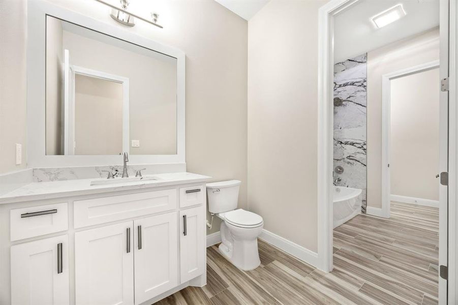 Full bathroom with toilet, tiled shower / bath combo, and vanity