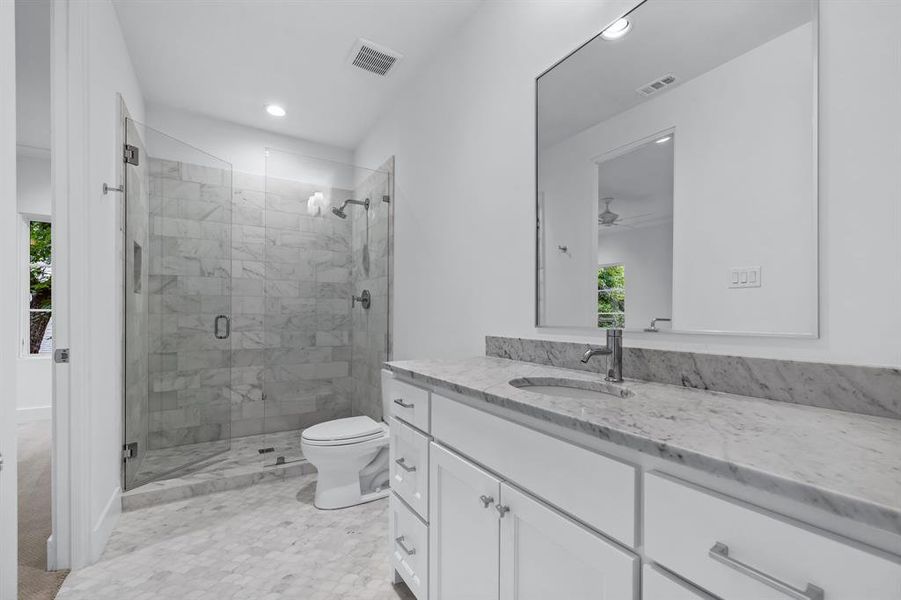 Bathroom with plenty of natural light, ceiling fan, toilet, a shower with shower door, and large vanity