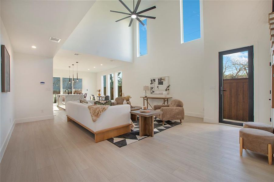 Living room featuring ceiling fan, light wood-type flooring, and a high ceiling