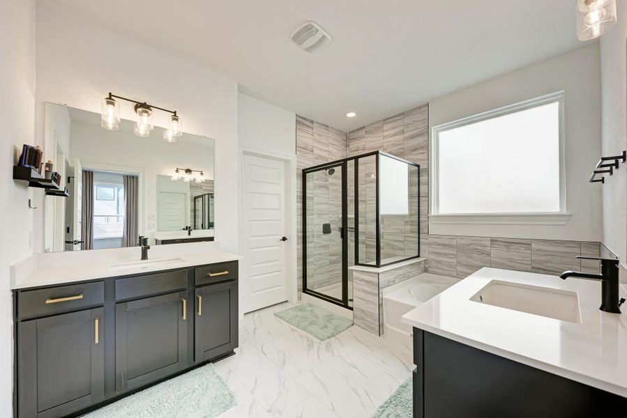 Full bathroom with a stall shower, two vanities, a bath, and light marble finish floors
