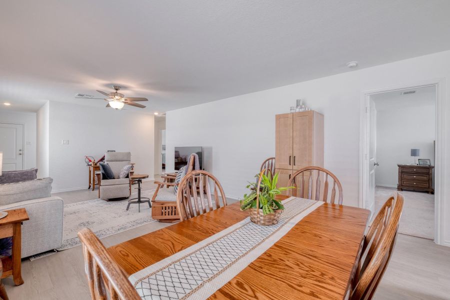 Open-concept living and dining area featuring light-colored walls, a ceiling fan, and light-toned flooring