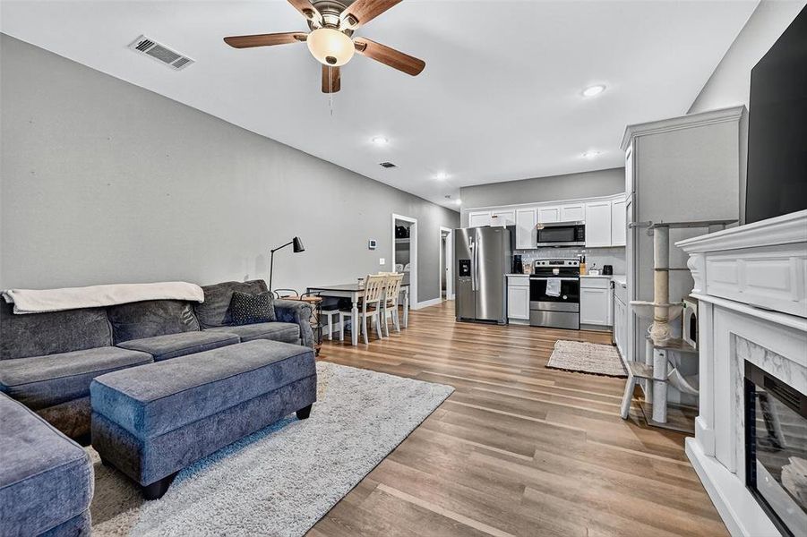 Living room with a ceiling fan, a fireplace, light wood-style floors, and recessed lighting Living room with a ceiling fan, a fireplace, light wood-style floors, and recessed lighting