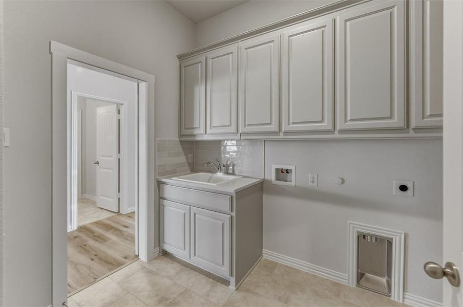Utility space featuring light gray cabinetry, a built-in sink with a countertop, tile flooring, and a subway tile backsplash Utility space featuring light gray cabinetry, a built-in sink with a countertop, tile flooring, and a subway tile backsplash
