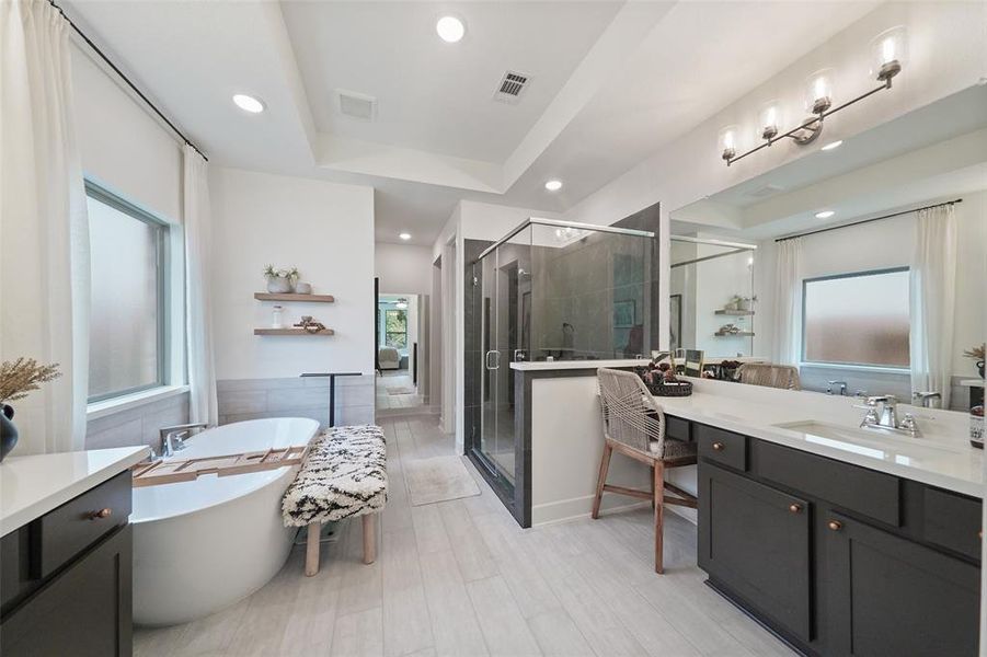 Primary bath, with vanity seating area. His and hers closets at end of bathroom on left and right.