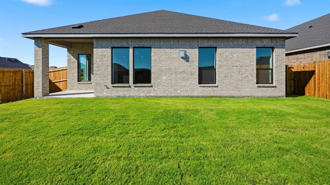 Back of property featuring a fenced backyard, brick siding, a shingled roof, and a patio area