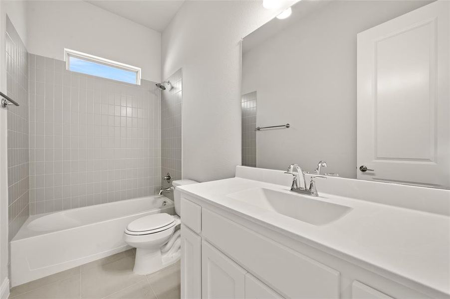 Bathroom with shower / bath combination, vanity, and light tile patterned flooring