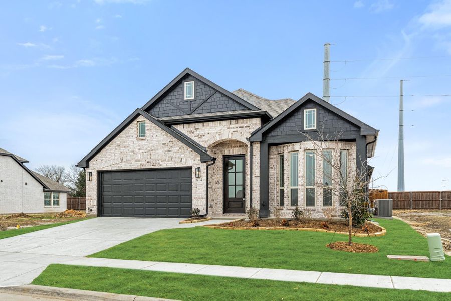 Single-story home with light brick exterior, dark trim, two-car garage, and arched front entry on corner lot