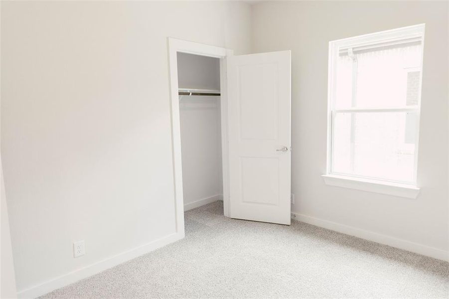 Unfurnished bedroom with light carpet and a closet