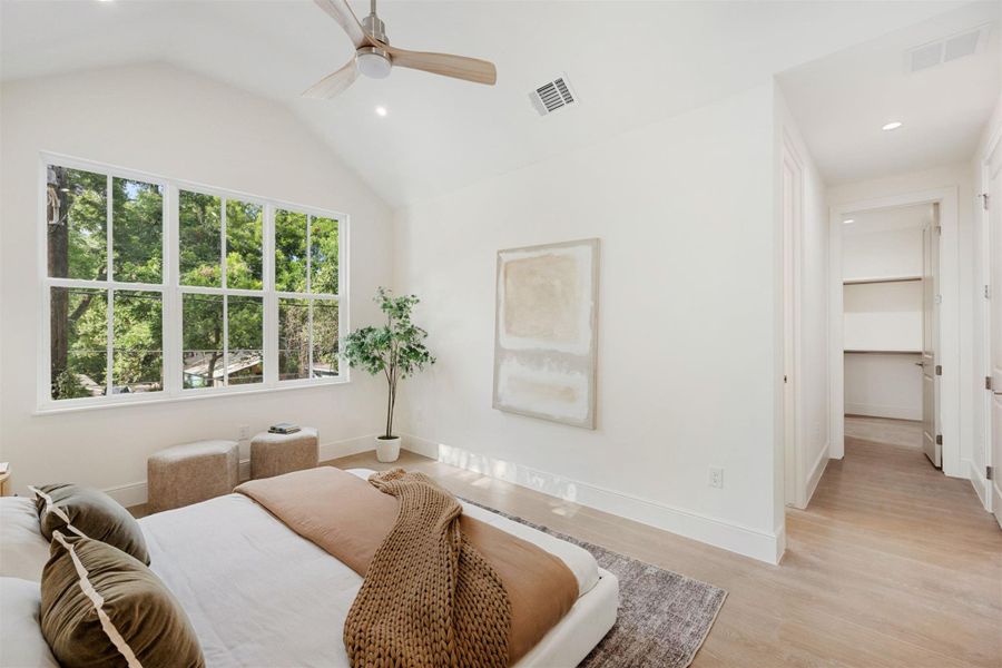 A tranquil bedroom retreat features a vaulted ceiling, abundant natural light, and a dedicated walk-in closet.