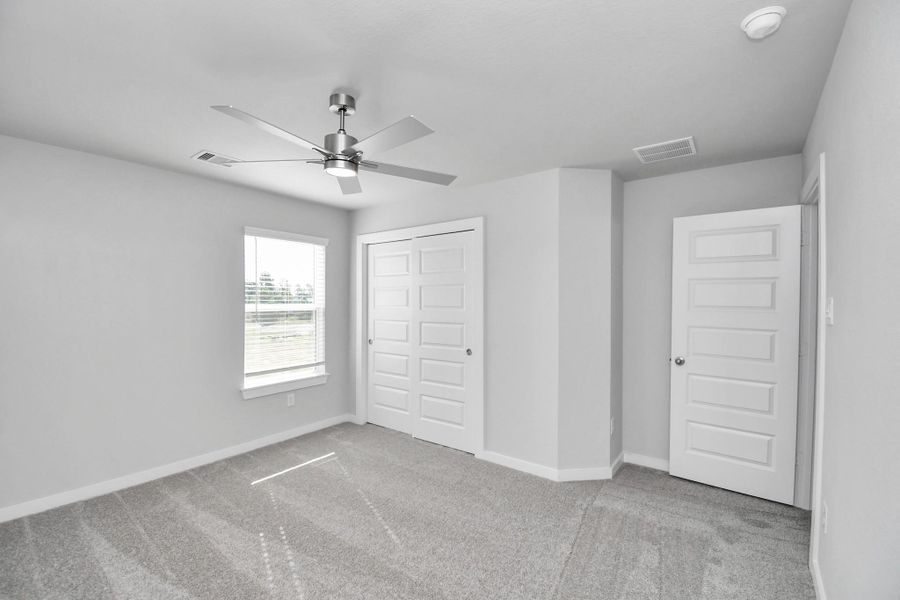 Secondary bedroom features plush carpeting, large windows that let in plenty of natural light, bright paint, and spacious closets. Sample photo of completed home with similar floor plan. Actual colors and selections may vary. Secondary bedroom features plush carpeting, large windows that let in plenty of natural light, bright paint, and spacious closets. Sample photo of completed home with similar floor plan. Actual colors and selections may vary.