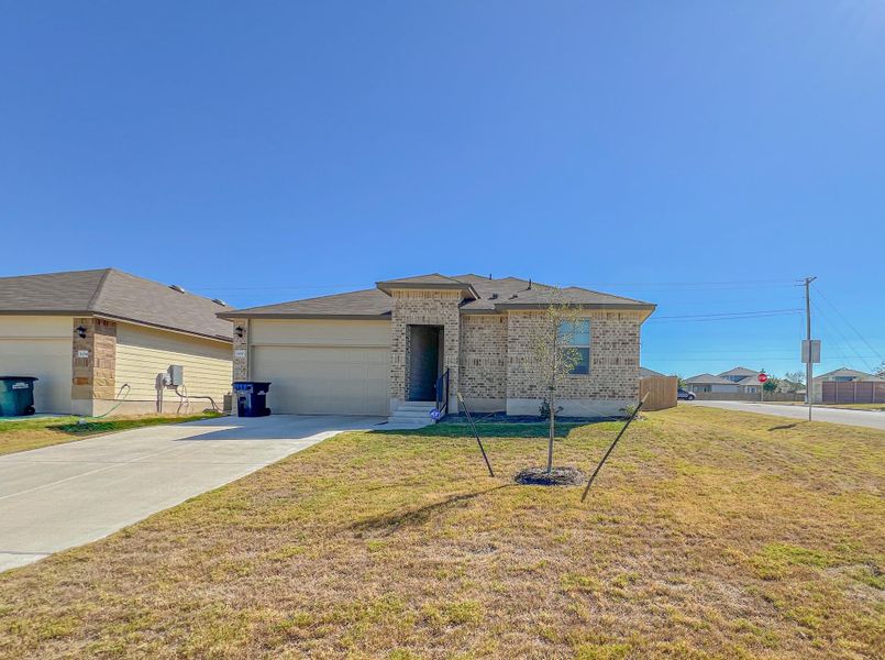 View of front of house with concrete driveway, brick siding, a front yard, and an attached garage