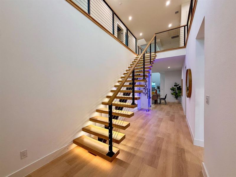 Staircase featuring wood finished floors, recessed lighting, and a towering ceiling