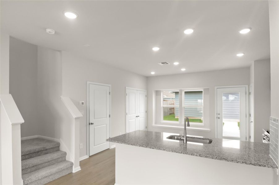 Kitchen featuring light stone countertops, recessed lighting, light wood-style flooring, and a peninsula Kitchen featuring light stone countertops, recessed lighting, light wood-style flooring, and a peninsula
