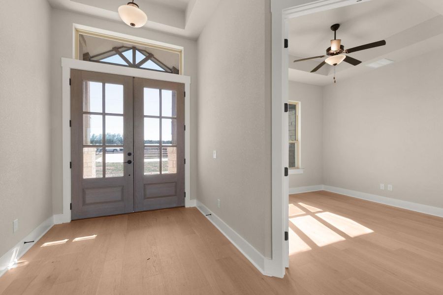 Entrance foyer with light wood finished floors, a ceiling fan, and french doors