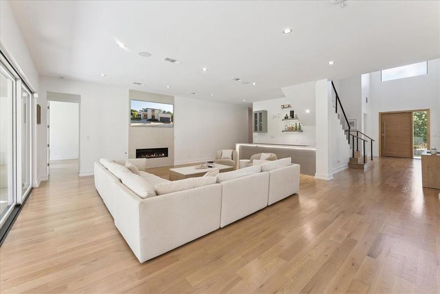 Living area featuring stairway, recessed lighting, light wood-style flooring, and a warm lit fireplace