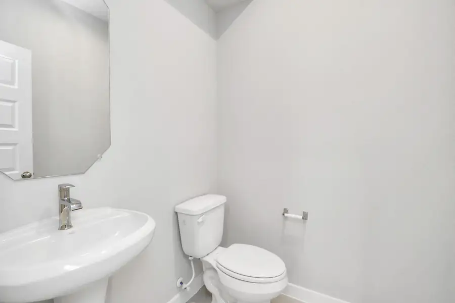 The half bathroom, conveniently situated on the 1st floor, is adorned with contemporary finishes. Custom wall paint, and a sleek faucet combine to create a bright and inviting space. Sample photo of completed home with similar floor plan. Actual colors and selections may vary.