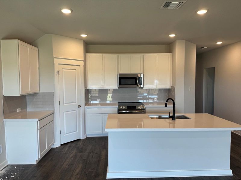 Kitchen with stainless steel appliances, dark wood finished floors, white cabinetry, recessed lighting, and decorative backsplash Kitchen with stainless steel appliances, dark wood finished floors, white cabinetry, recessed lighting, and decorative backsplash