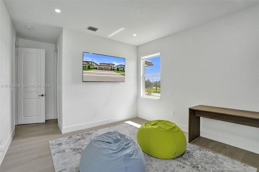 Recessed lighting, wood look flooring, white walls, built-in shelving, and a single window