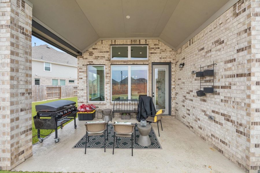 A covered rear patio with brick surround and vaulted ceiling provides shaded outdoor seating and direct access from the dining area.