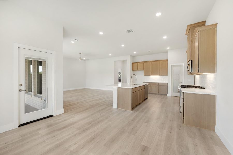 Open-concept kitchen and living area with light wood cabinets, center island, and light hardwood floors Open-concept kitchen and living area with light wood cabinets, center island, and light hardwood floors