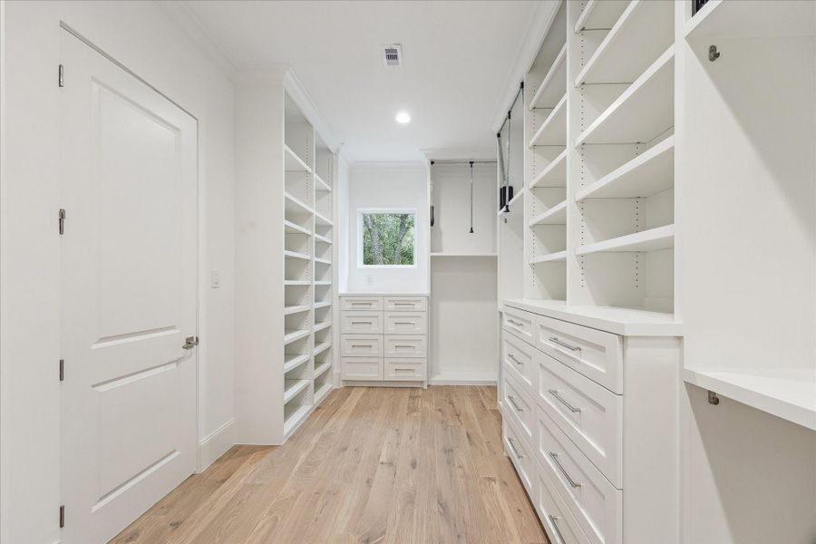 Primary closet complete with built-in shelving and drawers.