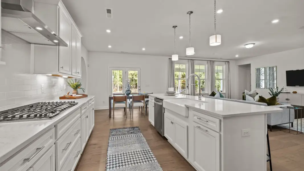 Gourmet kitchen with gas cooktop, vented hood, expansive island with quartz counter tops, in the Townsend Design by DRB Homes Gourmet kitchen with gas cooktop, vented hood, expansive island with quartz counter tops, in the Townsend Design by DRB Homes