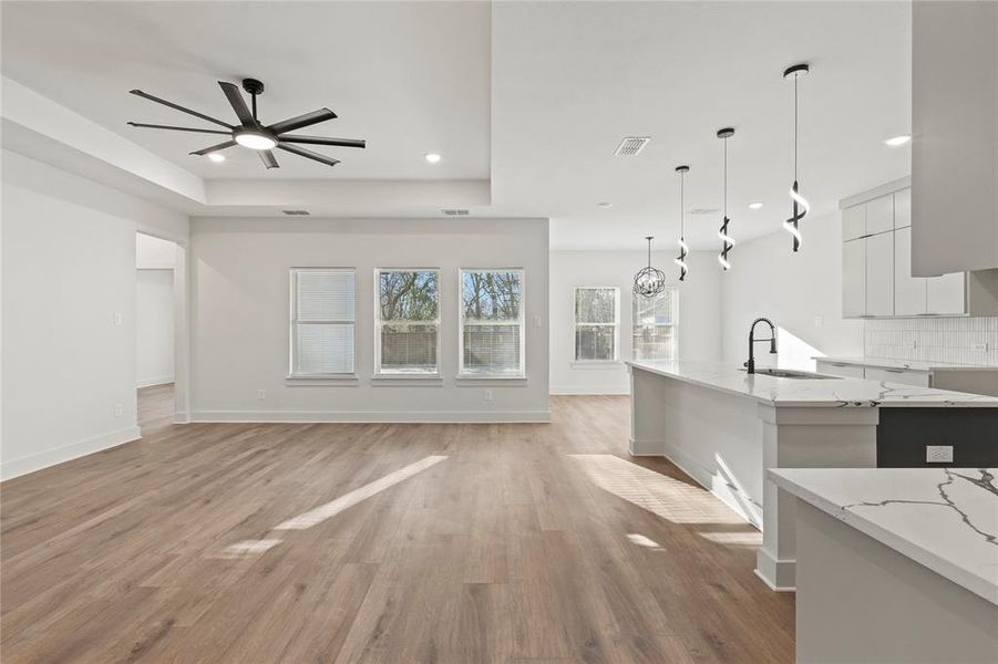 Kitchen with light wood-style floors, backsplash, modern cabinets, a raised ceiling, and pendant lighting