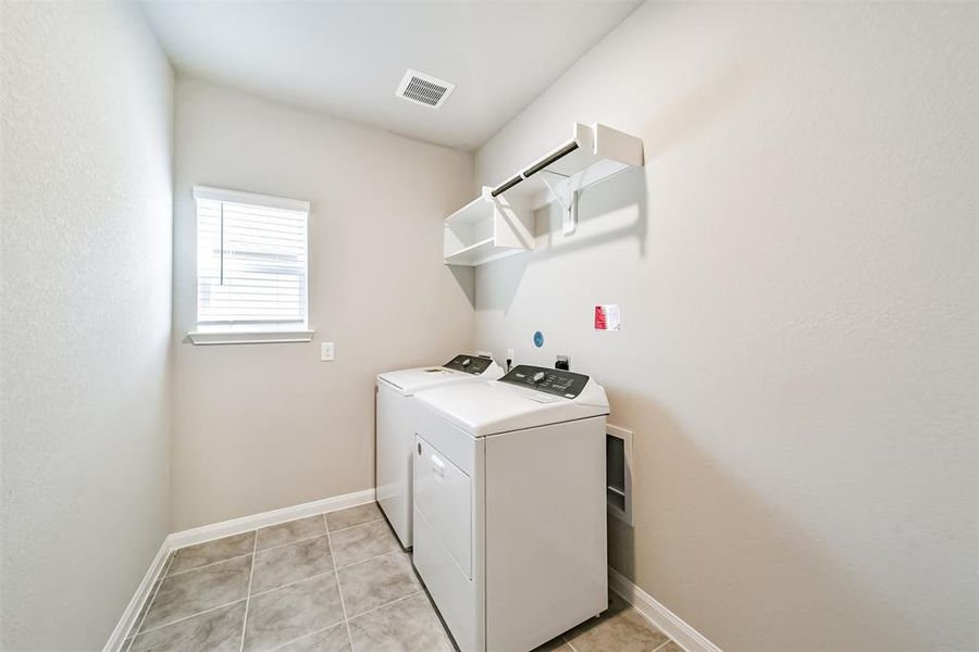 Convenient utility room including a washer & dryer combo, extra shelving, and plenty of space to set up a laundry space for getting chores done efficiently