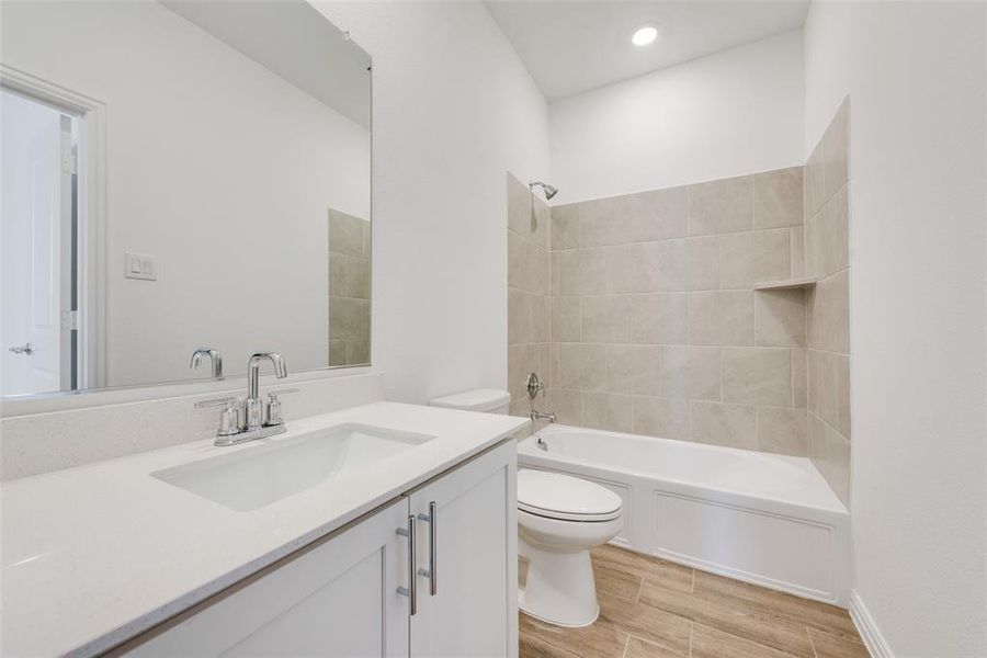 Full bathroom featuring toilet, tiled shower / bath, wood-type flooring, and vanity