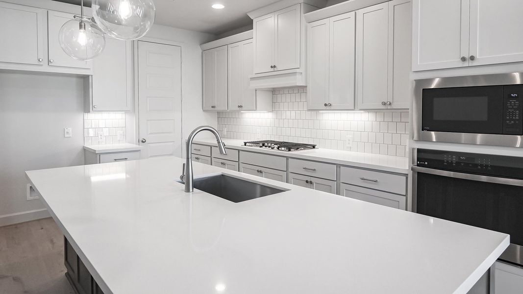 Kitchen with stainless steel appliances, decorative light fixtures, backsplash, white cabinets, and recessed lighting Kitchen with stainless steel appliances, decorative light fixtures, backsplash, white cabinets, and recessed lighting