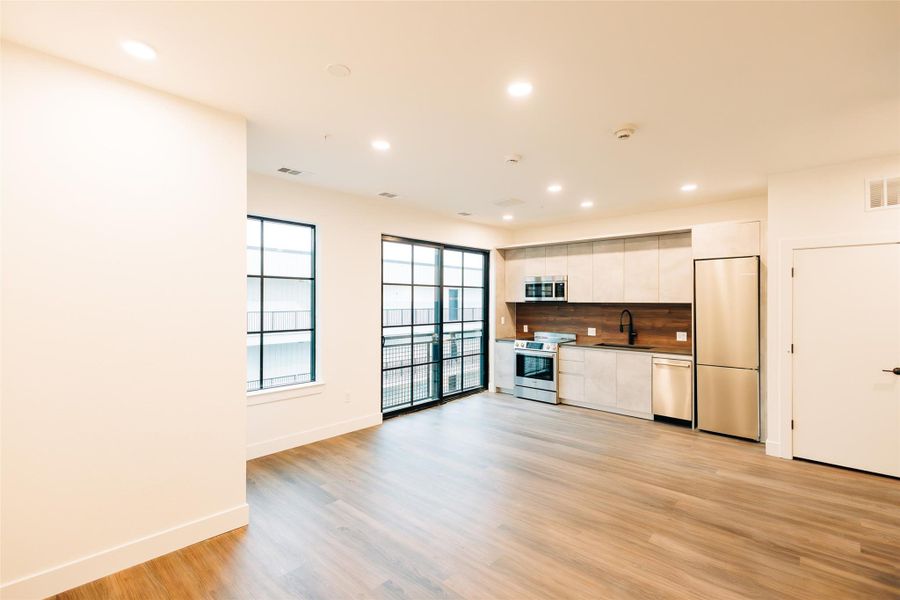 Kitchen with appliances with stainless steel finishes, white cabinets, recessed lighting, light wood-style flooring, and backsplash